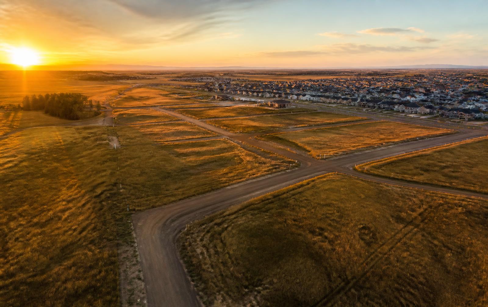 Aerial view of surveyed land parcels beside a growing housing development at sunset